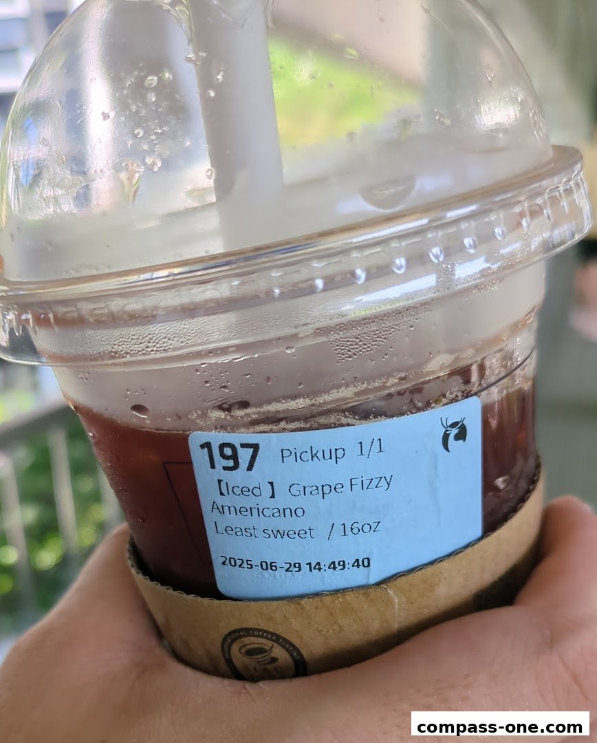 A hand holds a cold iced coffee with a label indicating the drink order.
