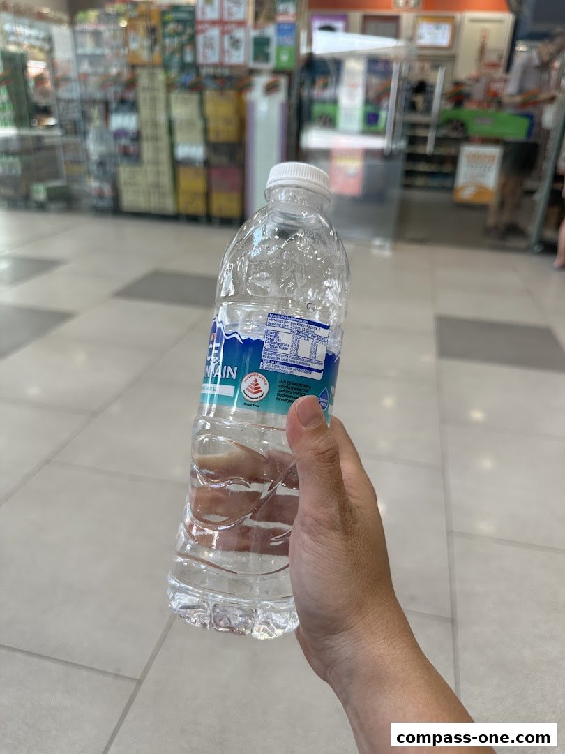 A hand holds a bottle of Ice Mountain water inside a 7-Eleven store.