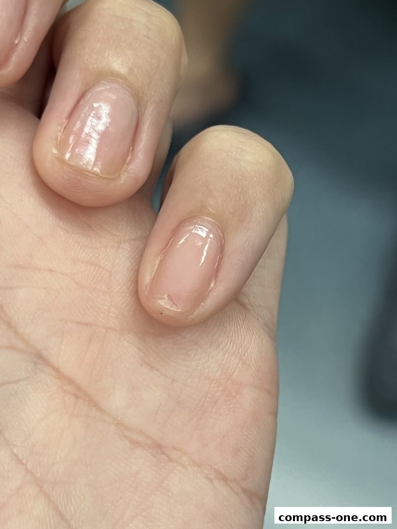 Close-up of a person's natural nails with a clear, glossy finish.