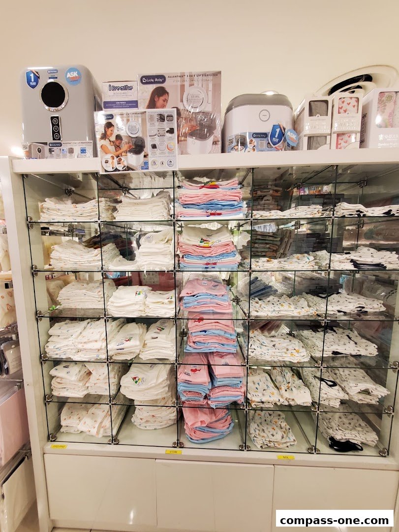 A display of folded baby clothes and baby sterilizers in a retail store.