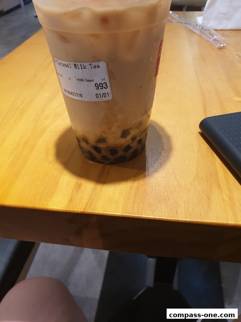 A close-up of a caramel milk tea with boba from Gong Cha on a wooden table.