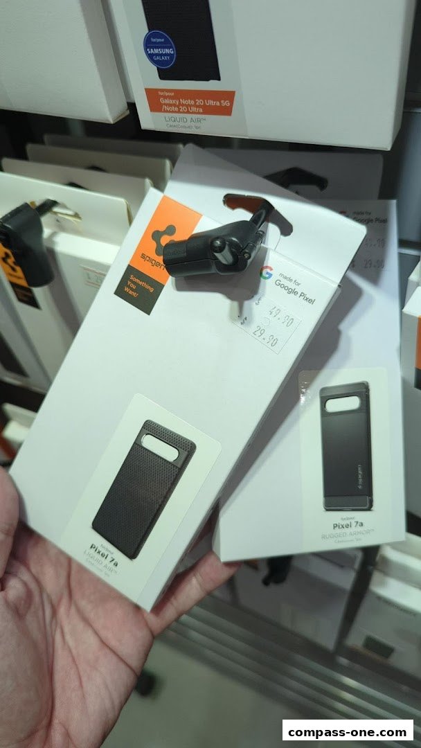 A hand holds a Spigen phone case for Google Pixel 7a, with other cases visible.
