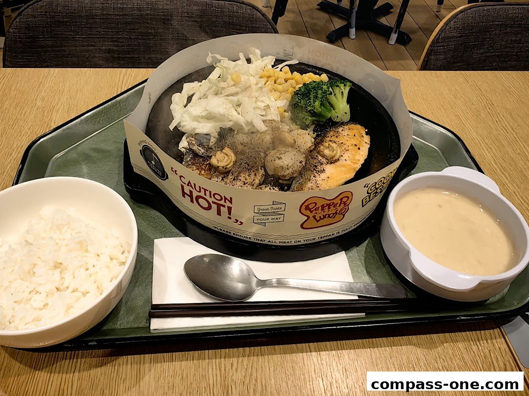 A sizzling hot plate meal with salmon, scallops, vegetables, rice, and sauce.