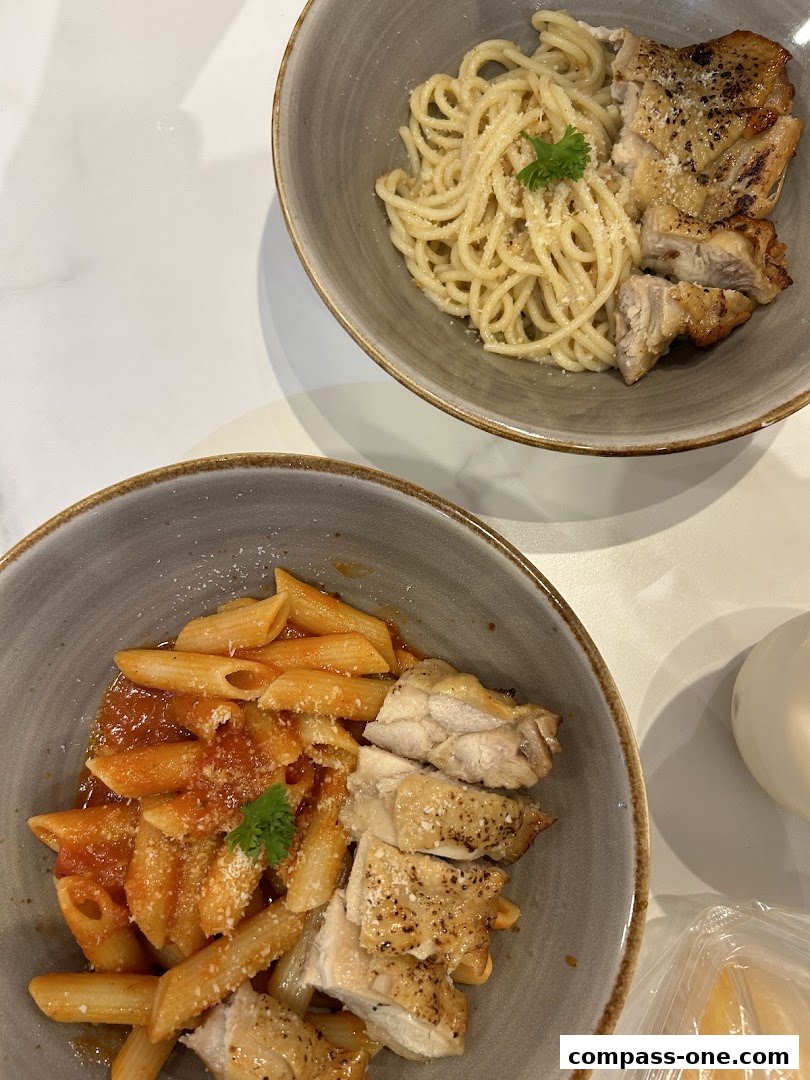 Two bowls of pasta with grilled chicken, one with tomato sauce and the other with a creamy sauce.