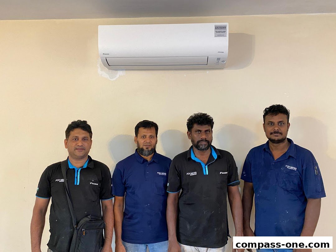 Four men in uniform stand in front of a Daikin air conditioner unit.