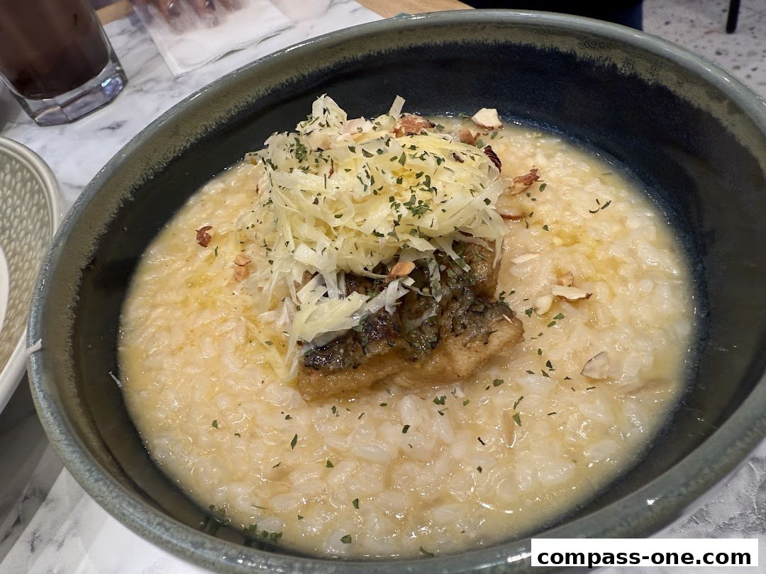 A close-up of a creamy risotto dish topped with shredded cheese, herbs, and a piece of fish.