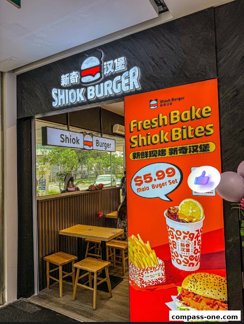 The exterior of Shiok Burger, a fast-food restaurant, with a prominent sign and a promotional poster.