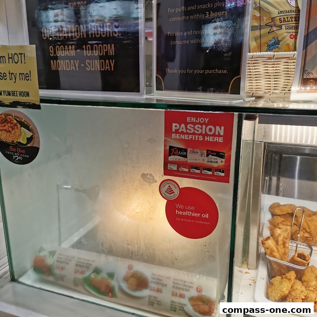 A display case at Tip Top Curry Puff showing various food items and promotional signs.