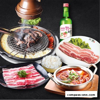 A spread of Korean BBQ dishes including grilled meat, pork belly, kimchi stew, rice, and soju.