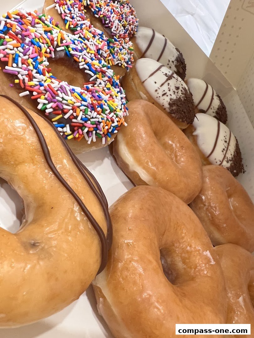 A box filled with assorted Krispy Kreme donuts, including glazed, sprinkle, and chocolate-iced varieties.