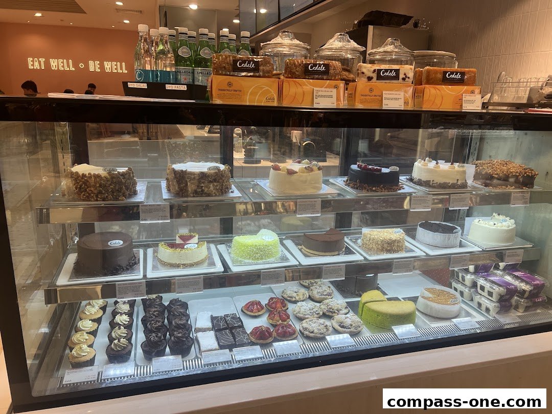 A display case filled with various cakes, cupcakes, and pastries at Cedele Bakery Cafe.