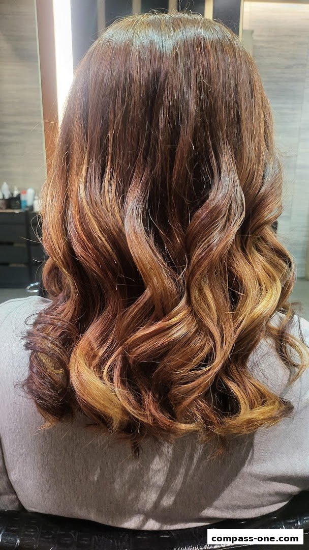 A person's back with beautifully styled, wavy, and colored hair.