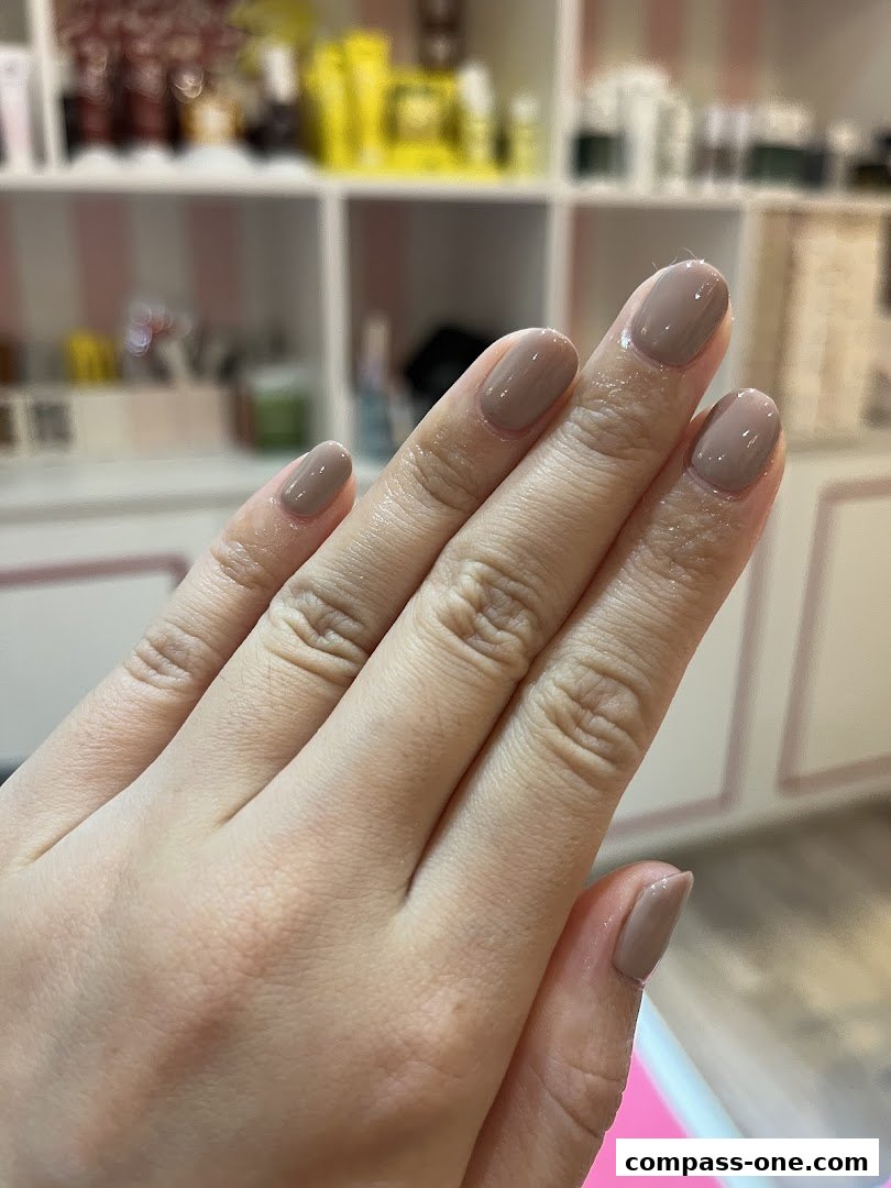 A close-up of a hand with perfectly manicured, neutral-toned nails.