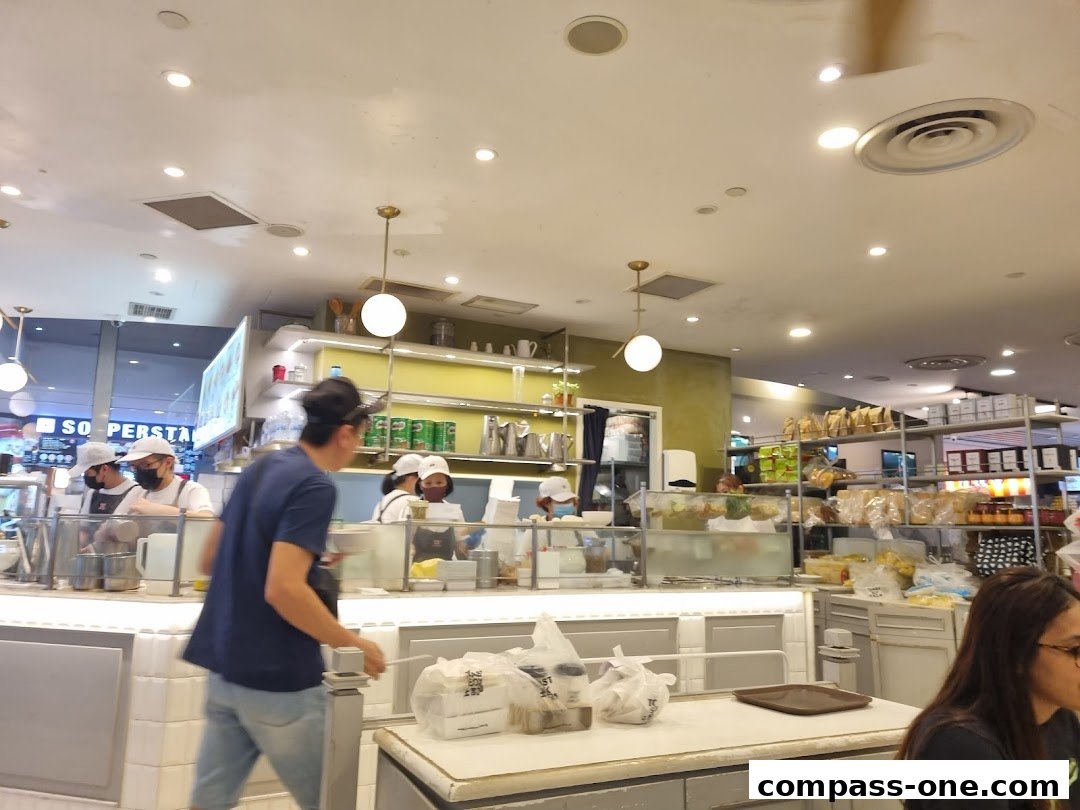 Interior view of a busy Toast Box cafe with staff serving customers and shelves stocked with products.