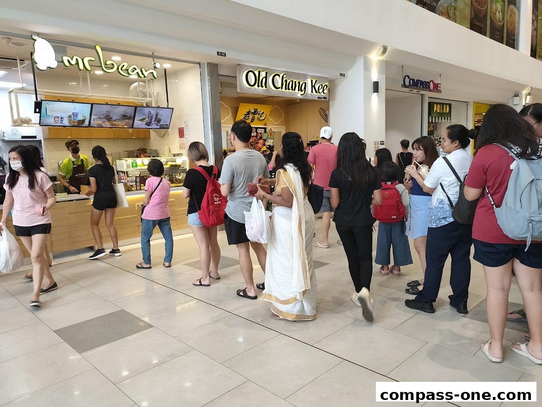 People queuing at Old Chang Kee and Mr Bean food stalls in a mall.
