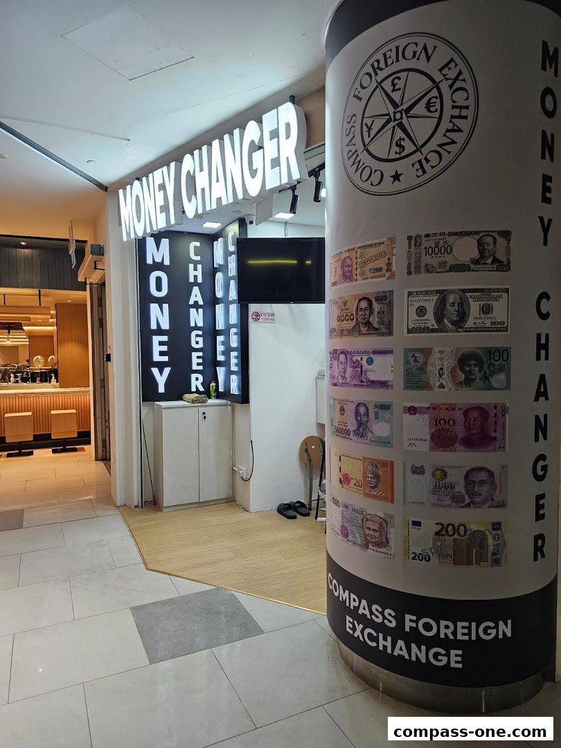 A brightly lit money changer shop with currency displays on a pillar and signage.