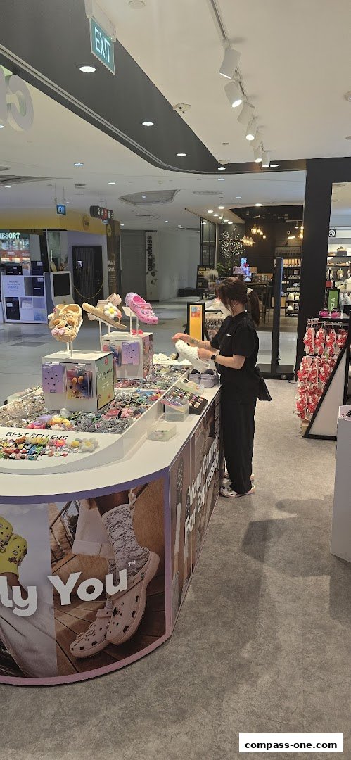 A Crocs store employee organizes Jibbitz charms and footwear displays.