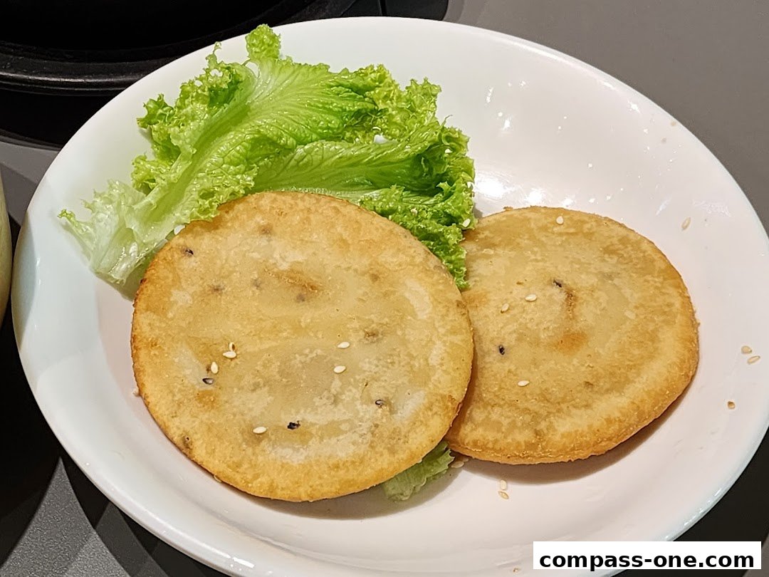 Two golden-brown Korean pancakes served with fresh lettuce on a white plate.