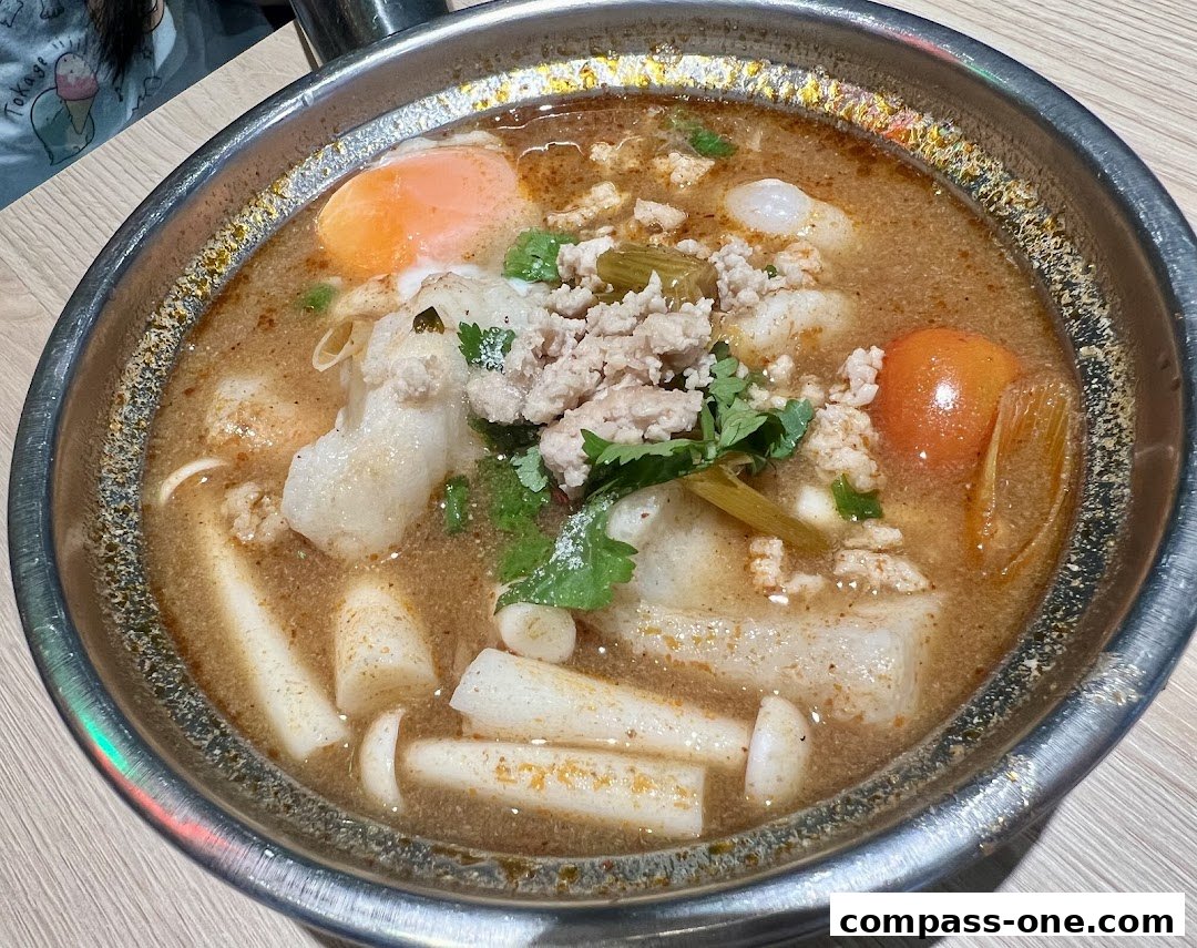 A close-up shot of a steaming bowl of flavorful noodle soup with minced meat and egg.