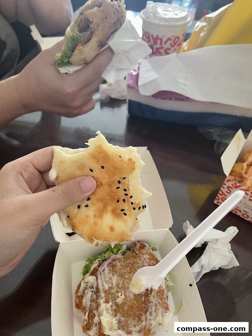 Hands holding delicious burgers and drinks, showcasing a satisfying meal experience.