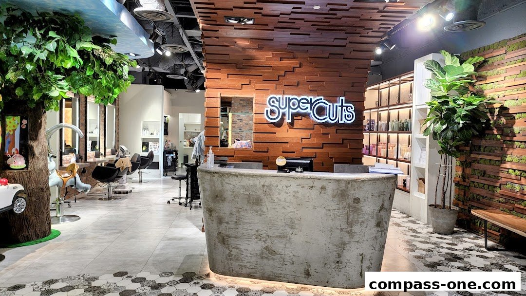 Interior view of a Supercuts salon with a reception desk, styling chairs, and decorative plants.