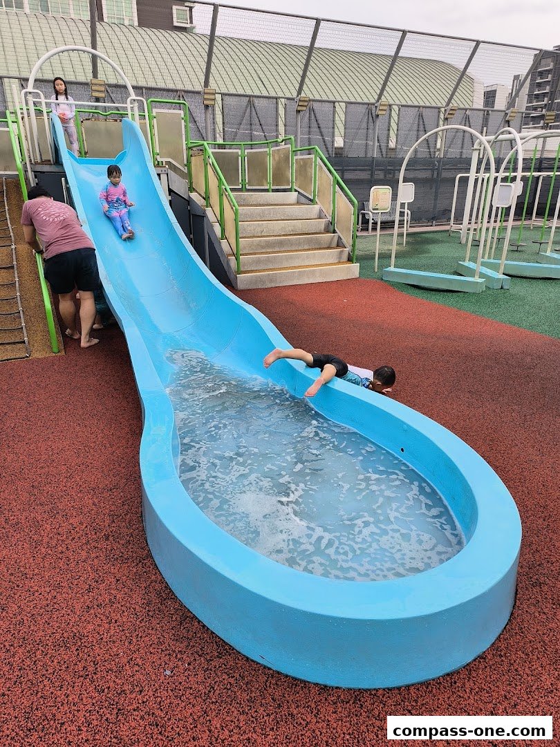 Children enjoying a water slide at an outdoor playground.