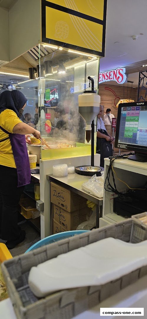A food stall worker prepares food while a POS system is visible.