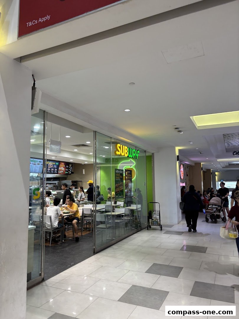 The Subway shop entrance with customers dining inside and a bright green sign.