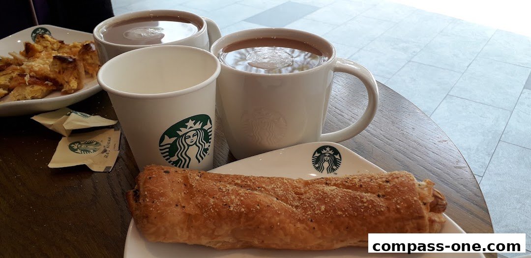 Starbucks coffee and pastries served on a wooden table with tiled flooring in the background.