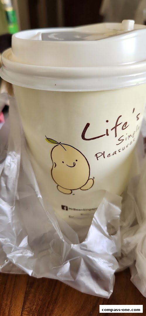 A close-up of a Mr Bean beverage cup with a cute bean character and text.