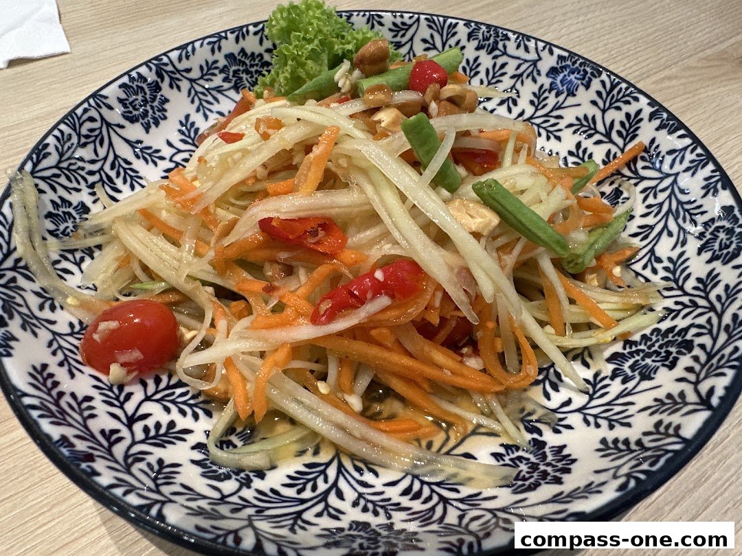 A close-up shot of a vibrant papaya salad served on a decorative blue and white plate.