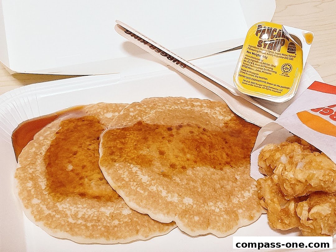 Burger King pancakes with syrup and hash browns in a takeaway box.