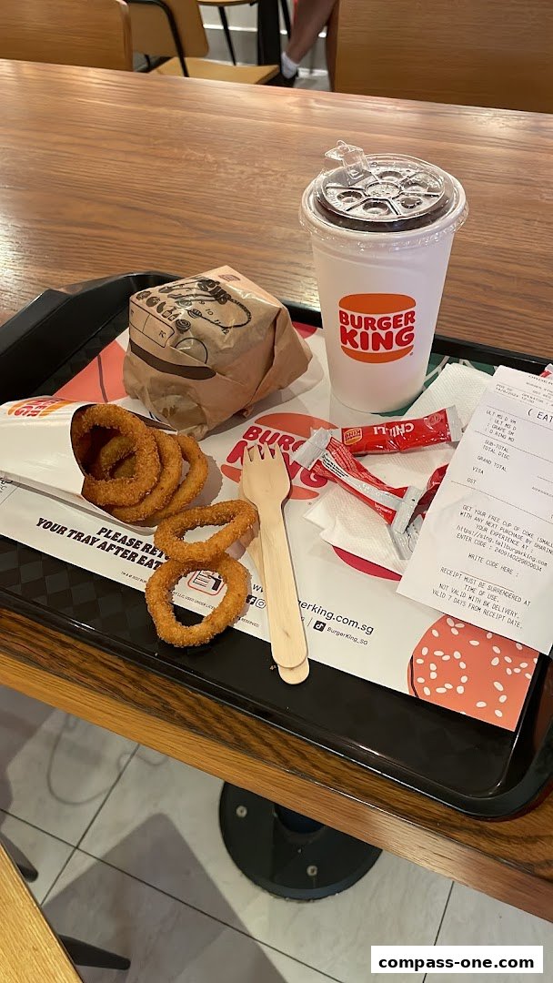 A Burger King meal with a burger, onion rings, a drink, and a receipt on a tray.