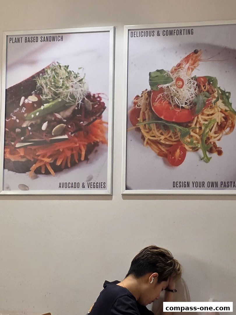 Two framed pictures of food, a sandwich and pasta, hang on a wall above a person.