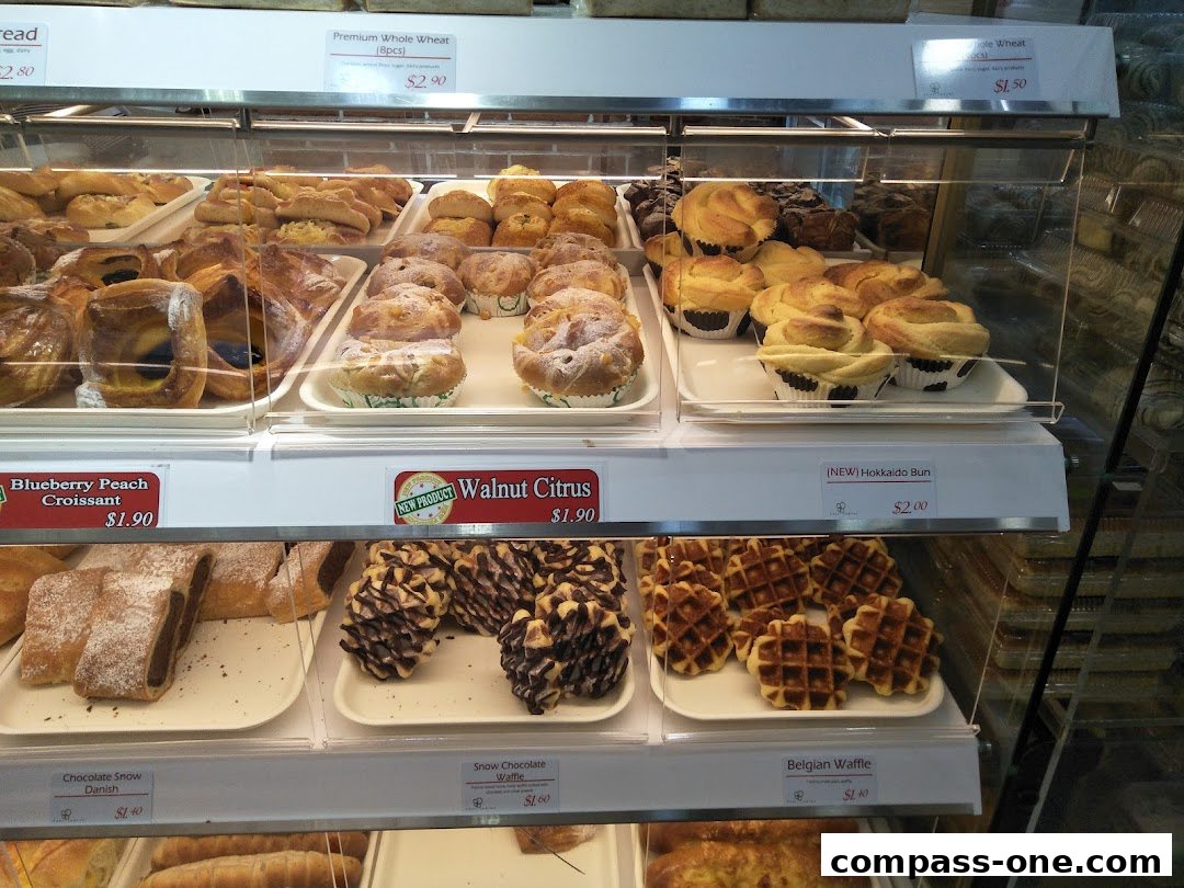A display case filled with various pastries, including croissants, buns, and waffles.
