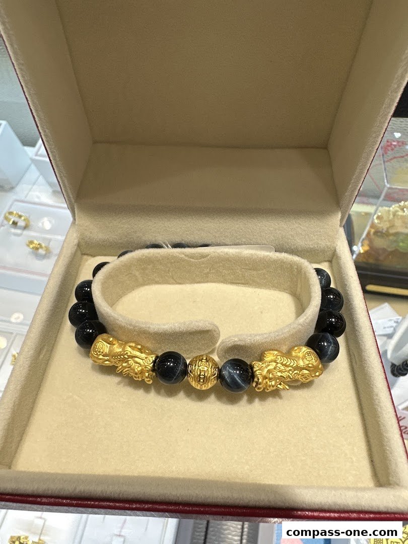 A gold and blue stone bracelet with Pixiu charms displayed in a jewelry box.