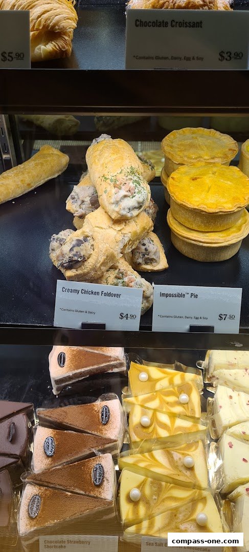 A display case filled with various pastries and cakes, including croissants, pies, and cheesecakes.