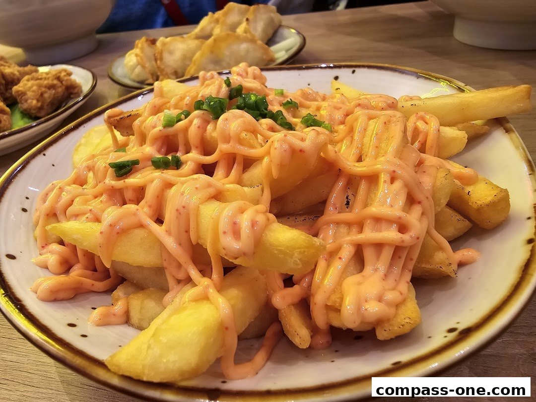 A plate of crispy fries generously drizzled with a creamy, spicy sauce and topped with chopped green onions.