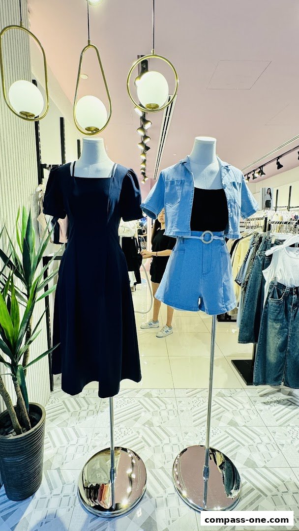 Mannequins display a navy dress and a denim outfit in a clothing store.