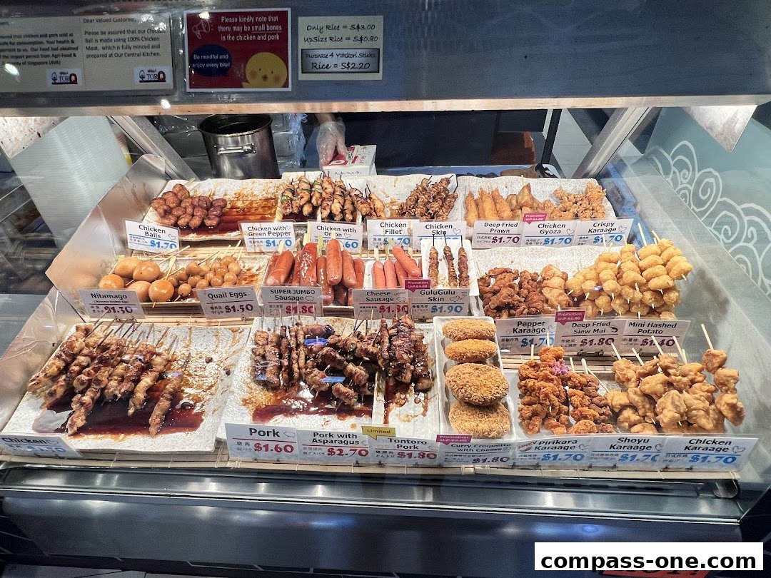 A display case filled with various Japanese skewers and fried items, labeled with names and prices.