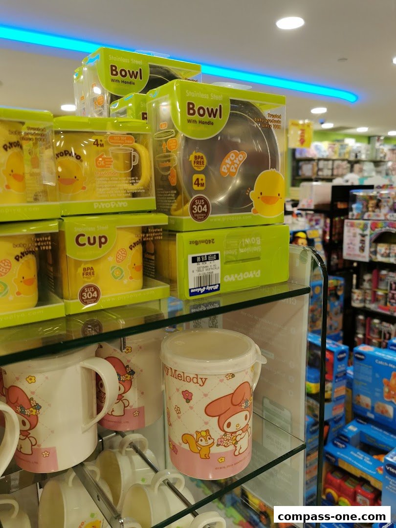 A display of baby feeding products including stainless steel bowls and cups with cute character designs.