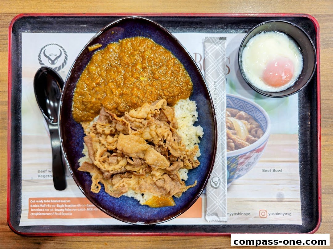 A Yoshinoya Beef Bowl with curry, rice, sliced beef, and a soft-boiled egg.