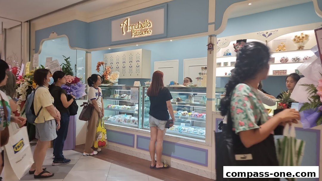 Customers queue at Annabella Patisserie Macarons, a charming shop displaying colorful macarons and cakes.