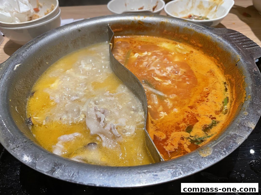 A split pot of hot pot broth with meat and vegetables.