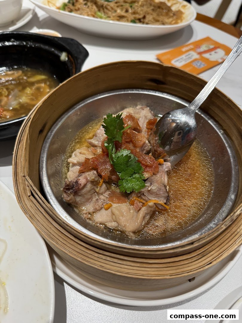 A close-up of a steaming dish of chicken in a bamboo steamer, garnished with cilantro.