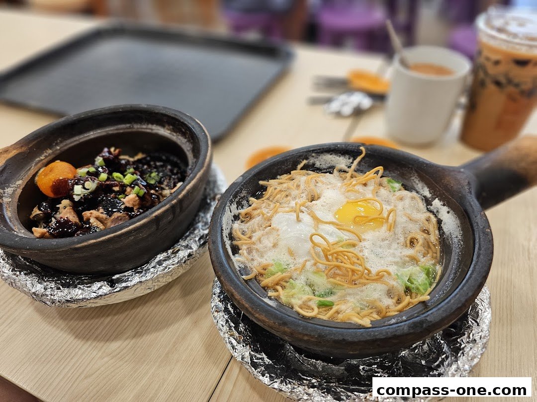Two clay pot dishes with noodles and meat, served with drinks.