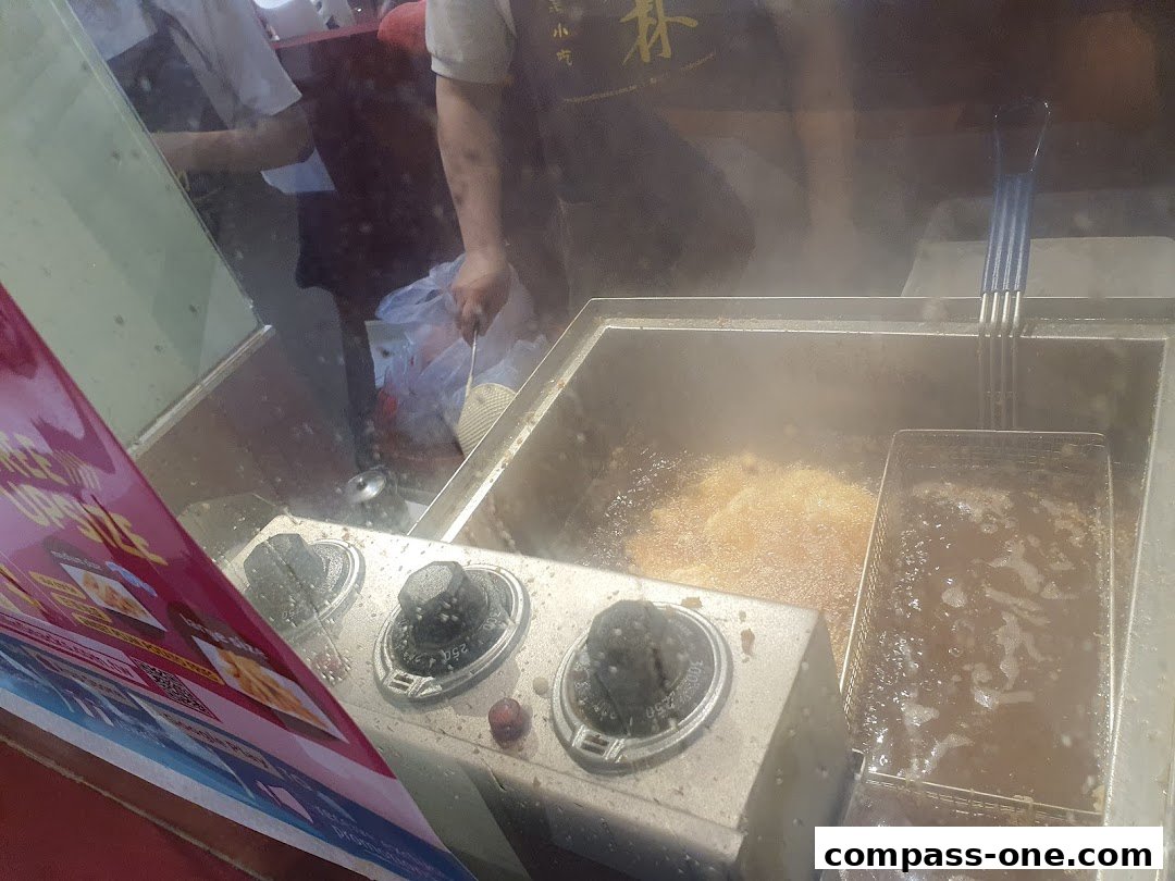 A deep fryer with bubbling oil and a person preparing food behind it.