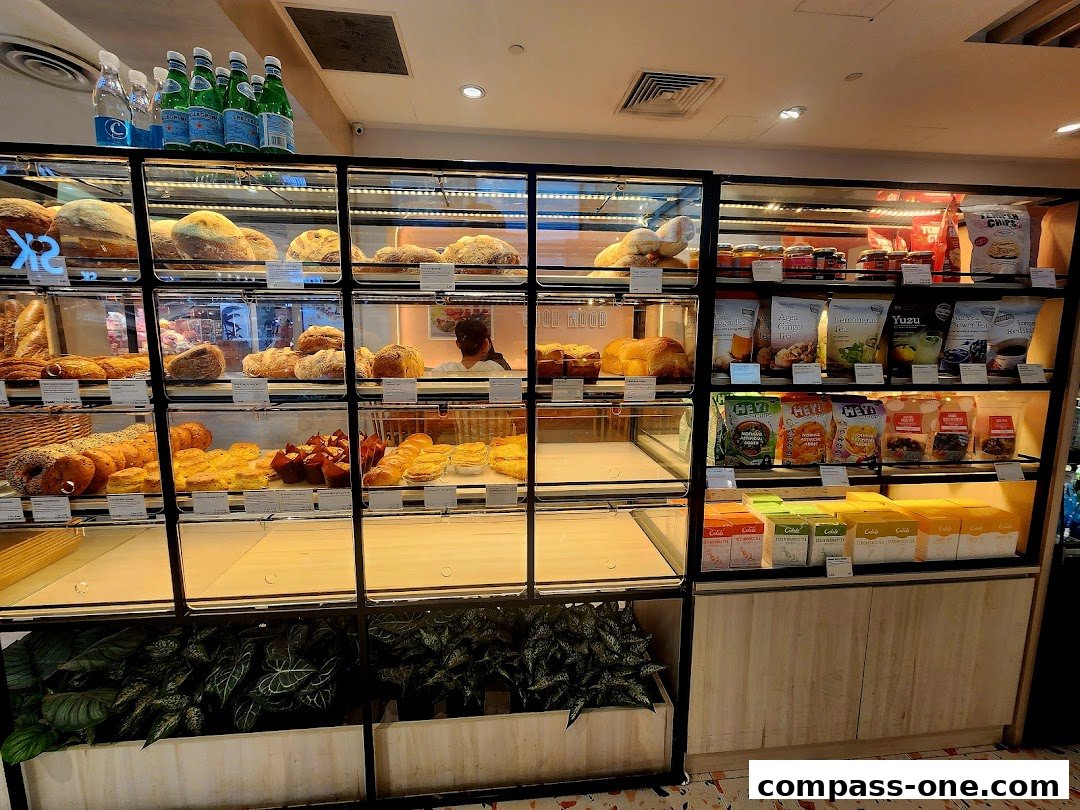 A display case filled with various baked goods, drinks, and packaged snacks at Cedele Bakery Cafe.