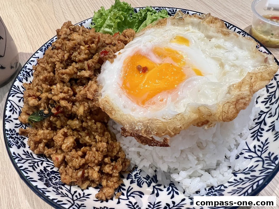 A plate of Thai basil minced chicken with rice and a fried egg.