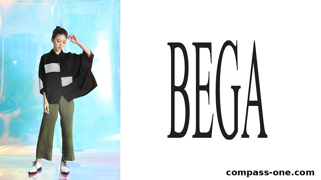 A model poses in BEGA fashion, showcasing a stylish black shirt and green pants.